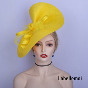 May include: A bright yellow hat with a large, floppy brim and a matching bow. The hat is made of a soft, textured fabric and has a slightly angled brim.