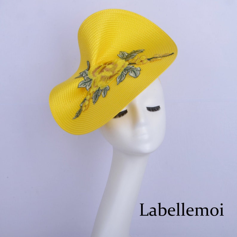 May include: A bright yellow hat with a floral design. The hat is made of straw and has a wide brim. The flowers are embroidered in yellow and green.