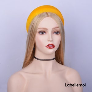 May include: A yellow velvet headband with a wide, rounded shape. The headband is worn on a mannequin with blonde hair.