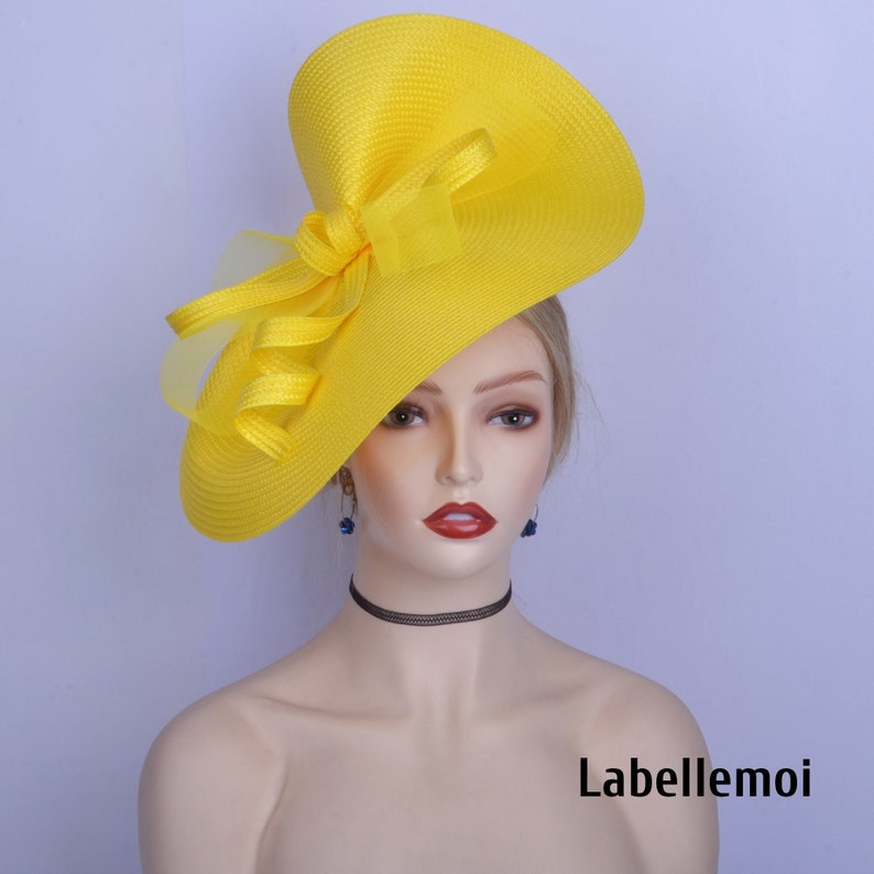 May include: A bright yellow hat with a large, floppy brim and a bow. The hat is made of a straw-like material and has a delicate, sheer fabric overlay.
