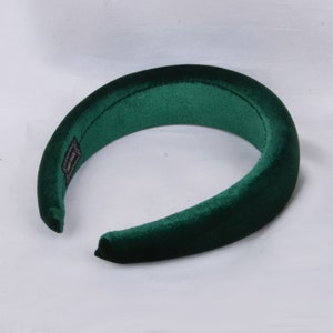 May include: A dark green velvet headband. The headband is thick and wide, and it is designed to be worn around the head.