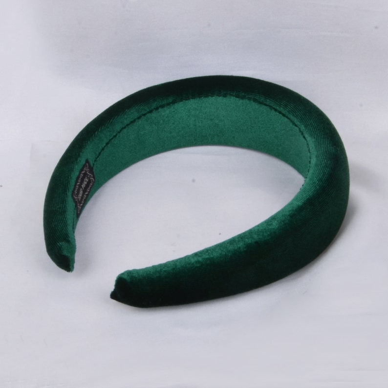 May include: A dark green velvet headband. The headband is thick and wide, and it is designed to be worn around the head.