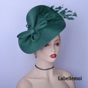 May include: A green hat with a large brim and a bow. The hat is decorated with green feathers.