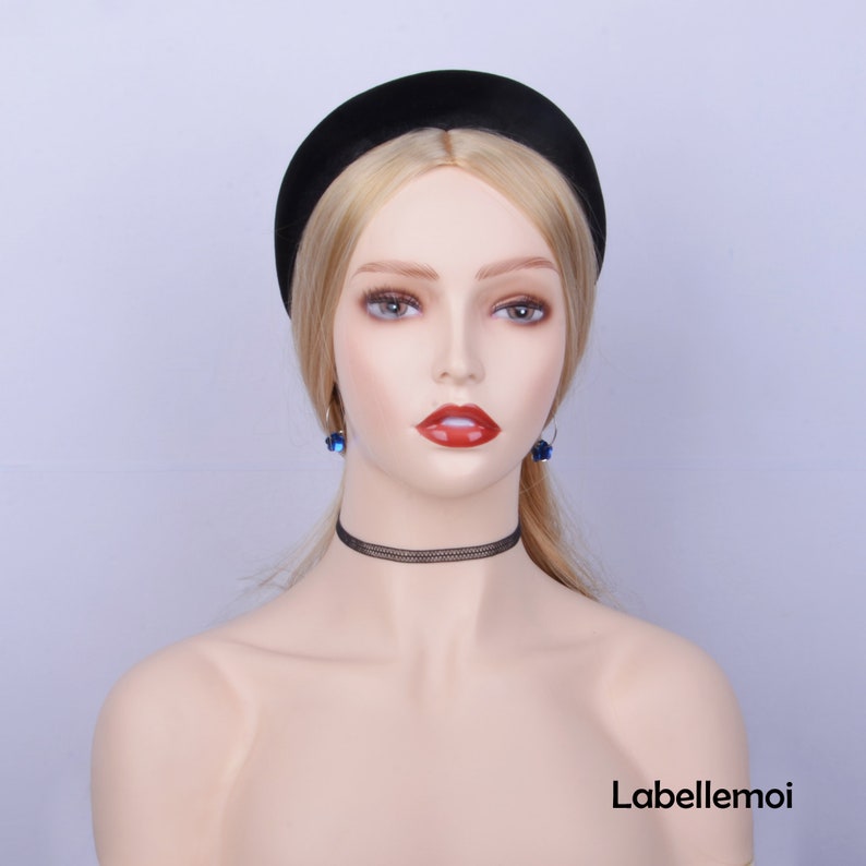 May include: A black velvet headband with a wide, padded band. The headband is worn by a mannequin with blonde hair and blue earrings.