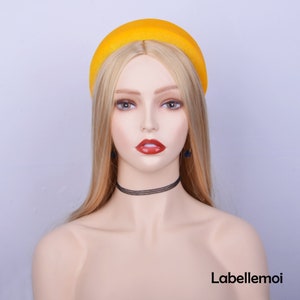 May include: A yellow velvet headband with a rounded shape. The headband is worn by a mannequin with blonde hair.