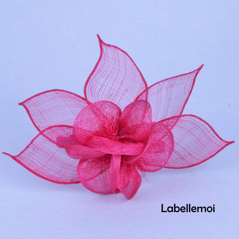 May include: A bright pink flower made of mesh fabric. The flower has a layered design and is perfect for adding a touch of color to any outfit.