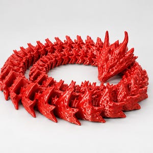 May include: A bright red articulated dragon figurine with a glossy finish. The creature is coiled in a circular shape, featuring a detailed head with horns and a segmented, flexible body composed of numerous overlapping, sharp-edged scales.