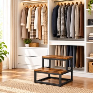 May include: A two-step stool featuring a dark brown wood-grain finish on the treads and a sturdy black metal frame. The stool is positioned in front of a white closet filled with hanging coats, blazers, and trousers on wooden hangers.