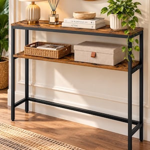 May include: A rectangular console table featuring a dark brown wood-grain finish top and lower shelf supported by a black metal frame. The table has two levels for storage and display, with four straight legs providing a stable, open-concept structure.