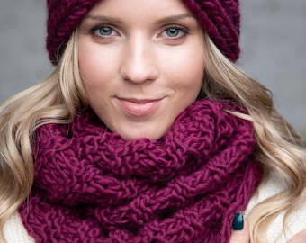 Puede incluir: Un conjunto de diadema y bufanda infinita de punto grueso en color magenta intenso. La bufanda presenta una pequeña etiqueta de cuero color canela con la letra B y el texto BARMINE impreso en negro. Tejido de textura gruesa.