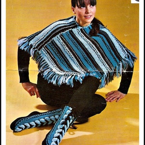 May include: A woman wearing a blue and brown striped poncho with fringe. She is sitting on a yellow surface and wearing blue crocheted boots.