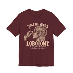 Puede incluir: Una camiseta de manga corta color granate con un gráfico de estilo vintage que muestra una cabeza humana con el cerebro expuesto y una mano sosteniendo un instrumento quirúrgico. El texto dice: TRUST THE SCIENCE, LOBOTOMY, A Brighter Tomorrow, EST. 1935.