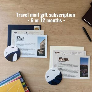 May include: A travel mail gift subscription set featuring two rectangular information cards titled Rome and Athens, each with a photograph and map. Includes two circular coasters with blue and white graphic designs and two envelopes.