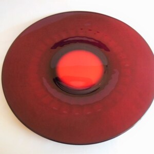 May include: A deep red glass plate with a smaller, concentric red circle in the center.