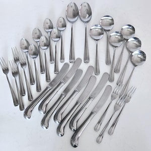 May include: A set of stainless steel silverware, including forks, knives, and spoons. The silverware is arranged in a fan shape on a white surface.