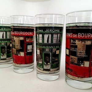 May include: Four clear glass tumblers with a red, green, and white design. Each glass features a storefront with the text "Chez Jerome" and "Restaurant 62". The text "Vins de Bourgogne" and "Bistrot a Vin" is also visible on the glasses.