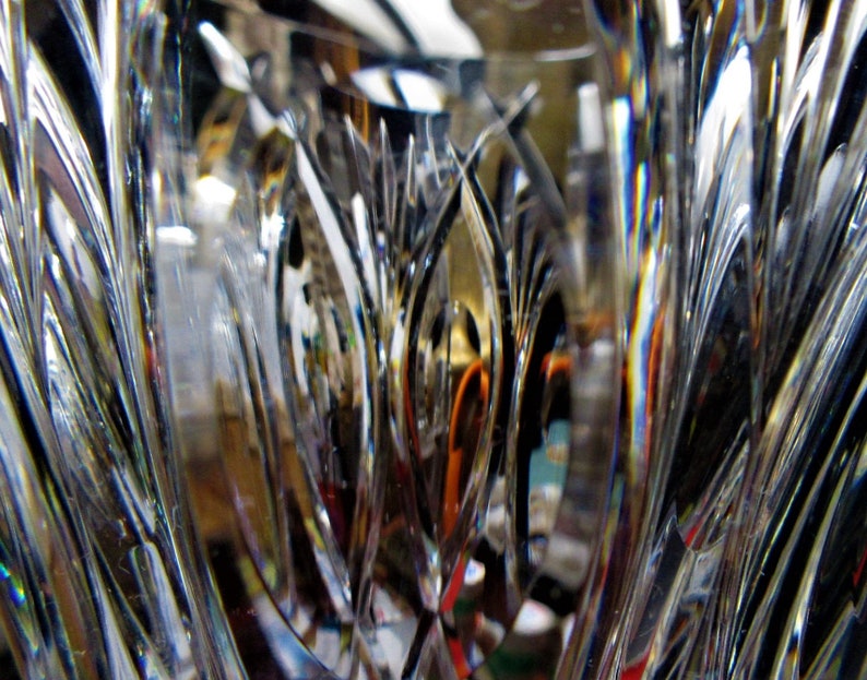 Puede incluir: Primer plano de un jarr&oacute;n de vidrio transparente con intrincados dise&ntilde;os tallados. La luz se refleja en el vidrio, creando un efecto arco&iacute;ris.