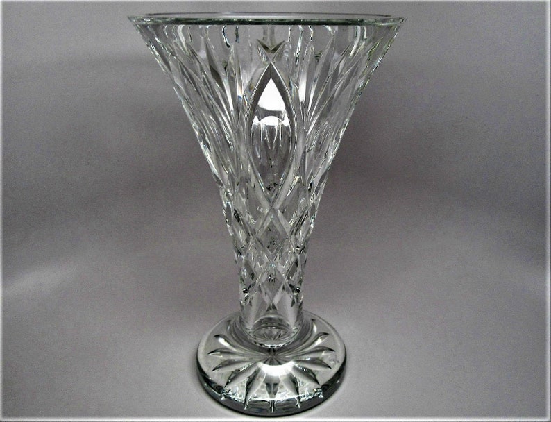 Puede incluir: Un jarr&oacute;n de vidrio transparente con un dise&ntilde;o de cristal tallado. El jarr&oacute;n tiene una boca ancha y una base estrecha.