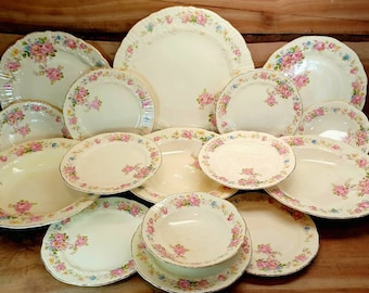 May include: A set of vintage floral patterned dinnerware, including plates, bowls, and saucers. The dishes are white with a delicate floral design in shades of pink, blue, and green.