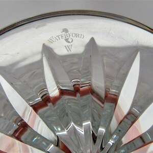 Puede incluir: Primer plano de la parte inferior de una copa de cristal Waterford. La copa tiene un patr&oacute;n de estrella y el logotipo de Waterford est&aacute; grabado en la parte inferior.