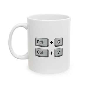 May include: A white ceramic mug featuring a graphic of two rows of computer keyboard keys. The top row displays Ctrl + C and the bottom row displays Ctrl + V in black text on grey keys, representing the copy and paste keyboard shortcuts.