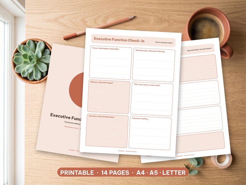 Printable executive function planner pages in terracotta laid out neatly on a wooden desk.