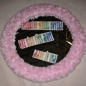 Puede incluir: Funda de volante de color rosa peludo con texto arco&iacute;ris que dice "Steering Wheel Covers", "One Size Fits Most" y "Made in USA".