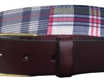 May include: A brown leather belt with a gold buckle and a plaid fabric lining. The fabric lining is a patchwork of different plaid patterns in blue, red, and white.