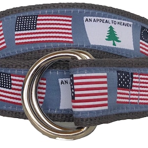 May include: A gray canvas belt with a silver buckle. The belt is decorated with repeated images of the American flag and a flag with a pine tree and the text "An Appeal to Heaven".