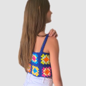 May include: A blue crochet top with colorful granny squares. The top has thin straps and a cropped length.