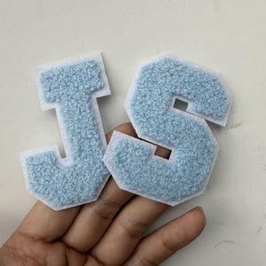Puede incluir: Dos parches de letras estilo universitario, J y S, con un centro de felpa azul claro texturizado y un borde de fieltro blanco. Estos parches para planchar o coser están diseñados con una fuente de bloque clásica y una superficie elevada.