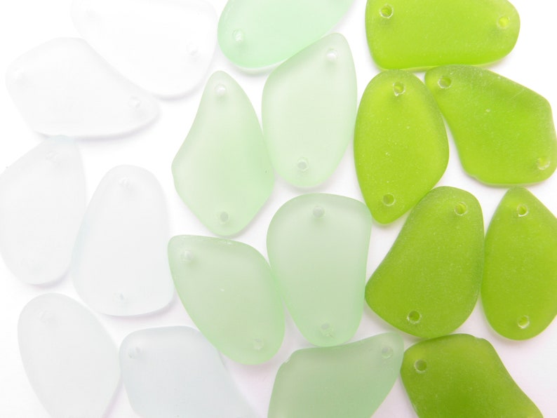 May include: A collection of smooth, frosted glass beads in shades of green and white. The beads have a teardrop shape with a hole at the top for stringing.