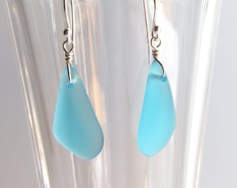 May include: A pair of silver dangle earrings with light blue teardrop-shaped glass beads.