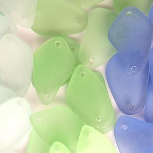 May include: Assortment of sea glass pieces in various shades of blue, green, and white. The sea glass is smooth and translucent, with a frosted finish.