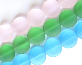 May include: Close-up of a strand of colorful, round beads. The beads are in shades of pink, green, and blue. The beads have a matte finish and are strung together, creating a visually appealing pattern.