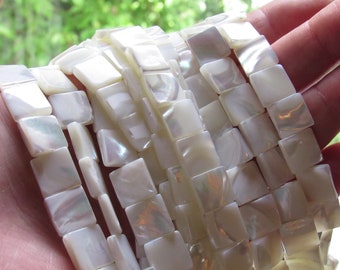 May include: A strand of white square-shaped shell beads. The beads have a pearlescent finish and are strung on a clear thread.