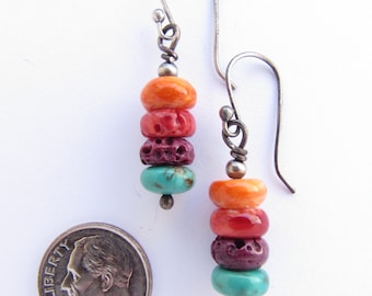 May include: A pair of silver dangle earrings with a stack of colourful beads. The beads are orange, red, purple, and turquoise. The earrings are about the size of a ten pence piece.