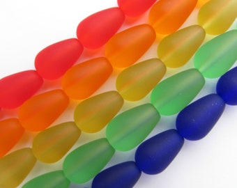 May include: A rainbow assortment of frosted glass beads in the shape of teardrops. The beads are arranged in rows, with each row featuring a different color, starting with red and ending with blue.