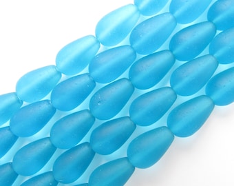 May include: Rows of light blue, teardrop-shaped beads. The beads have a frosted, matte finish and are strung together. The beads are a vibrant, solid color and are arranged diagonally across the frame.