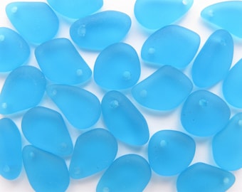 May include: A collection of light blue glass beads with a hole in each bead. The beads are smooth and have a frosted finish.