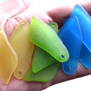 May include: A collection of translucent, frosted glass pendants in yellow, lime green, and bright blue. Each piece features an irregular, elongated shape with a single pre-drilled hole at one end, suitable for jewelry making or decorative craft projects.