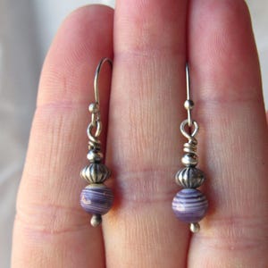 May include: A pair of silver dangle earrings with purple and white striped shell beads.
