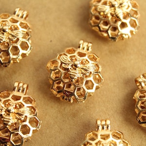 Puede incluir: Siete abalorios de metal dorado en forma de panal de abejas con un diseño de abeja. Cada abalorio tiene un bucle para sujetarlo a un collar o pulsera.