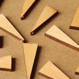 May include: A collection of wooden triangle shapes with a brown edge. The triangles are various sizes and are arranged on a brown surface.