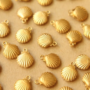 May include: A collection of gold-colored metal seashell charms with a loop for attaching to jewelry or other crafts.