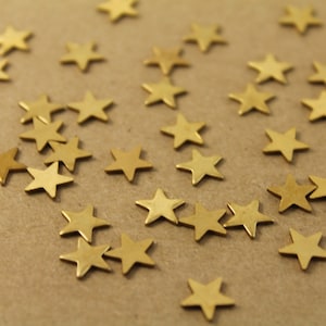 May include: A scattering of gold star-shaped embellishments on a brown paper background.