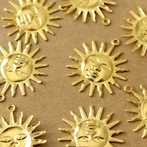 May include: A collection of gold-colored metal sun charms with a face design. Each charm has a loop for attaching to a necklace, bracelet, or other jewelry.
