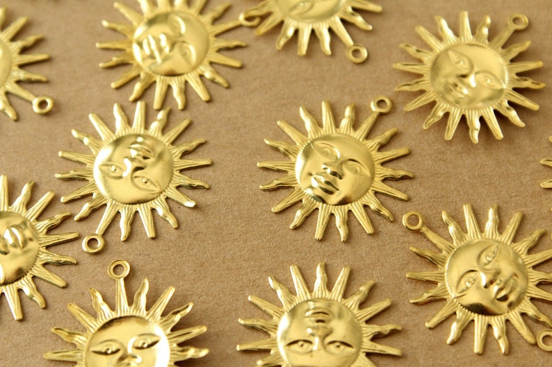 May include: A collection of gold-colored metal sun charms with a face design. Each charm has a loop for attaching to a necklace, bracelet, or other jewelry.