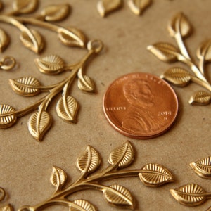 May include: Gold-toned metal leaf sprigs with a penny for scale. The sprigs have a delicate, intricate design and are perfect for adding a touch of elegance to crafts and jewelry.