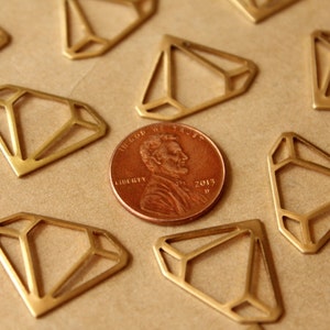 May include: A close-up of a collection of gold-coloured metal diamond shapes on a brown surface. A US penny coin with the words "In God We Trust" and "Liberty" is in the centre of the image.